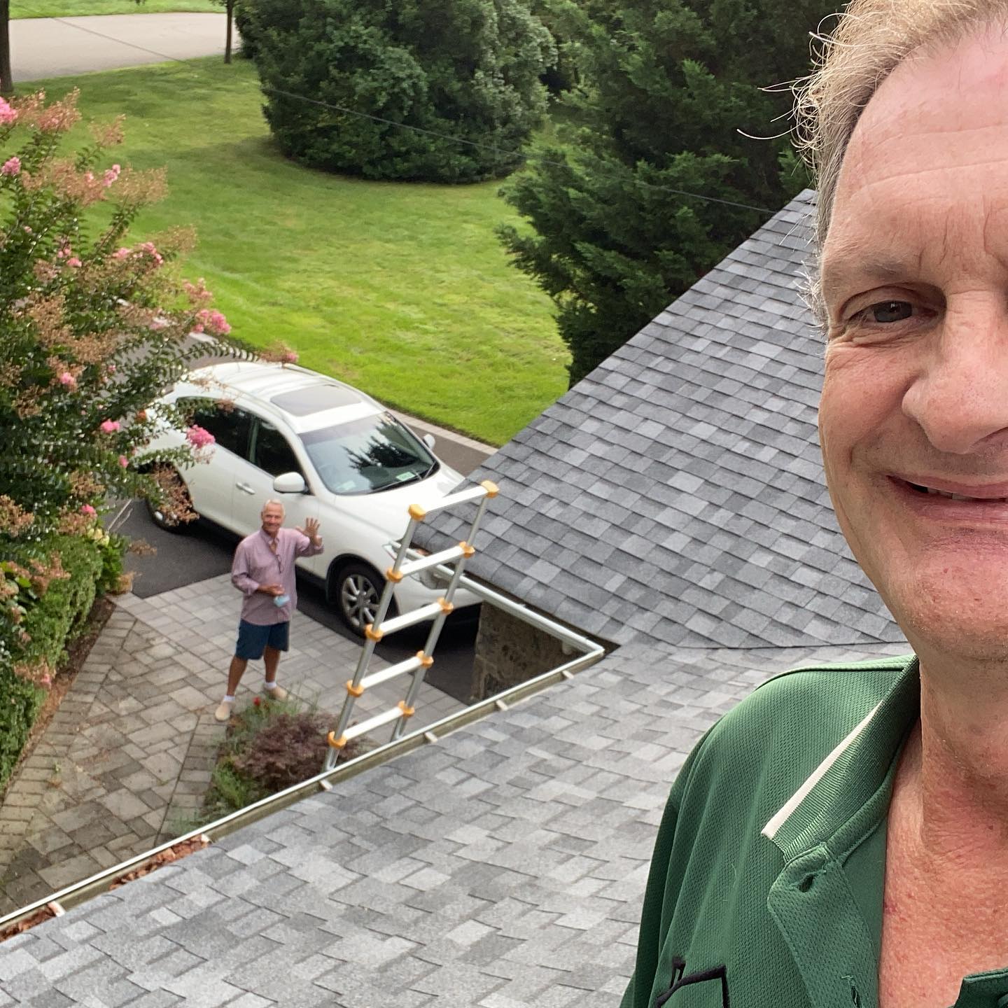 Selfie of John inspecting a new rood with a real estate agent on the ground waving