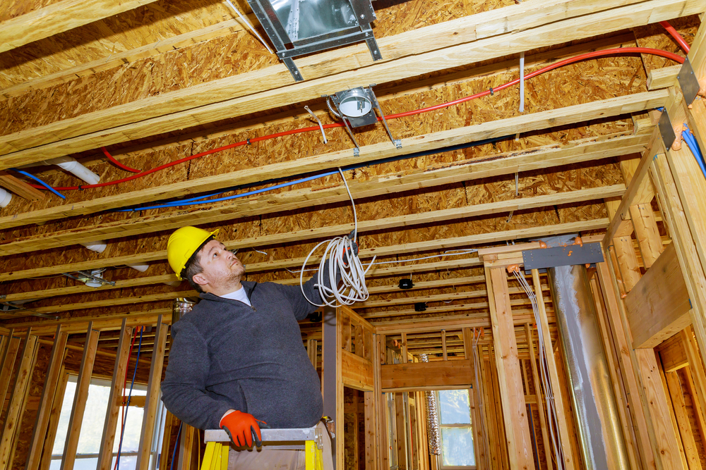 Electrician installing electrical cable wire in new house construction site