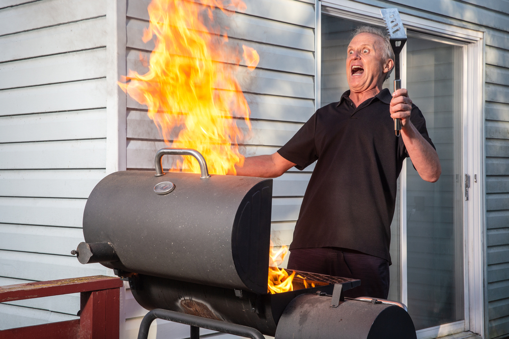 man reacting to explosive fire in barbecue
