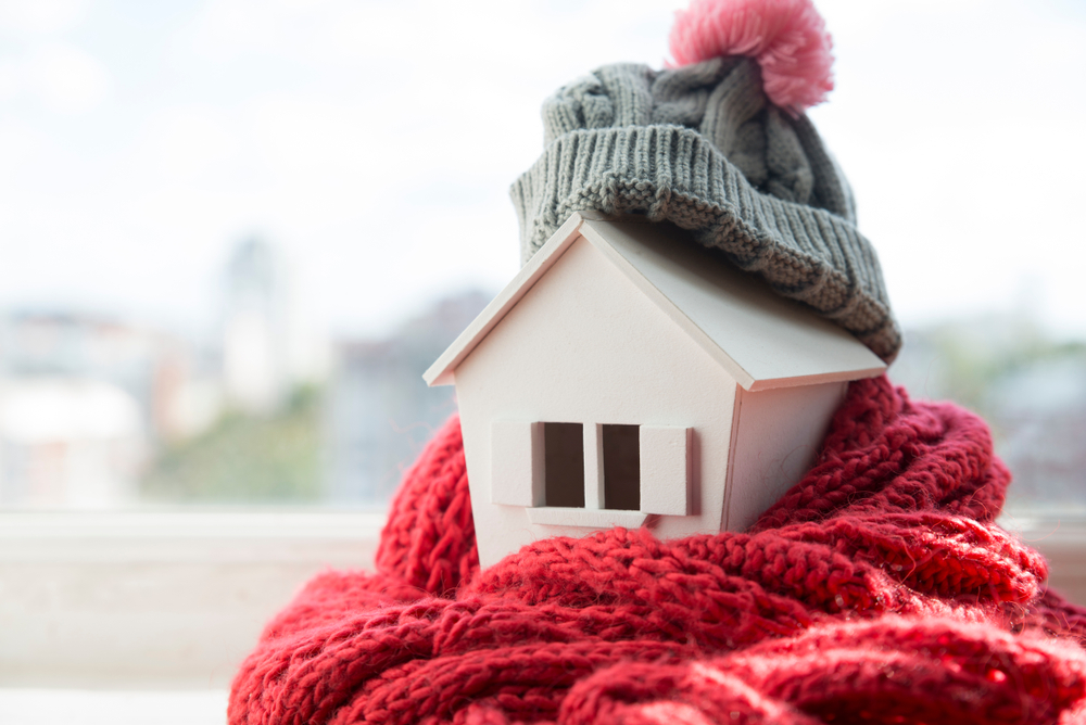 Small wooden house rapped in a hat and scarf to show it is protected from the winter elements