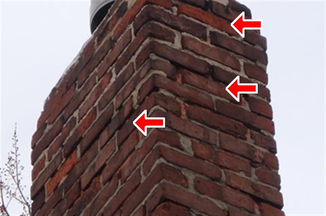 Picture of chimney from home inspection report showing damaged masonry. Red arrows point to the problems areas.