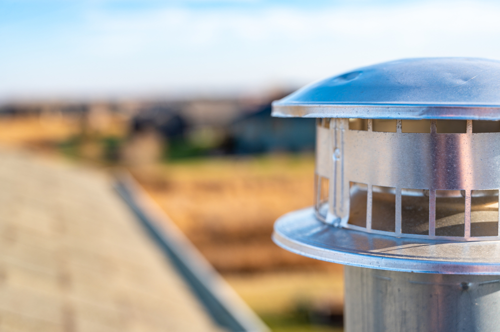 Typical rooftop chimney with a rain cap and shielding